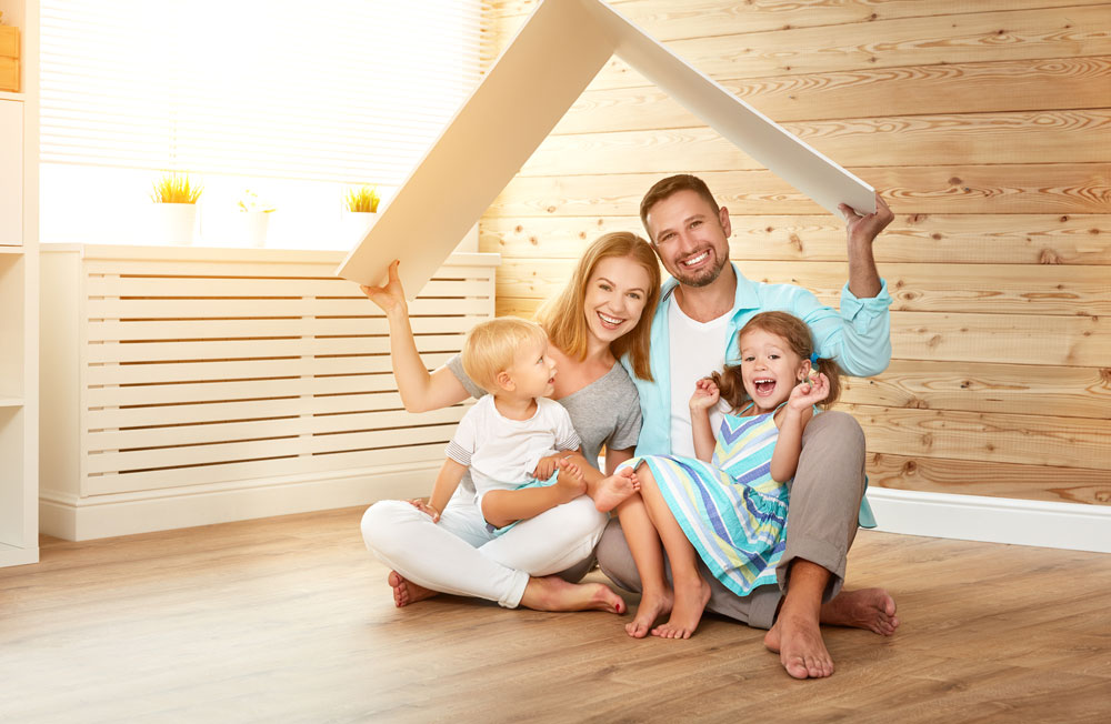 Family holding small wooden roof over their heads