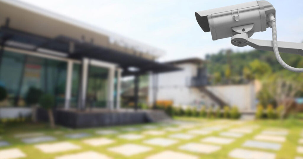 An outdoor security camera with a house in the background