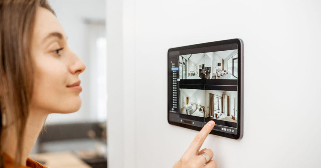 A woman monitors her home on a tablet installed on a wall